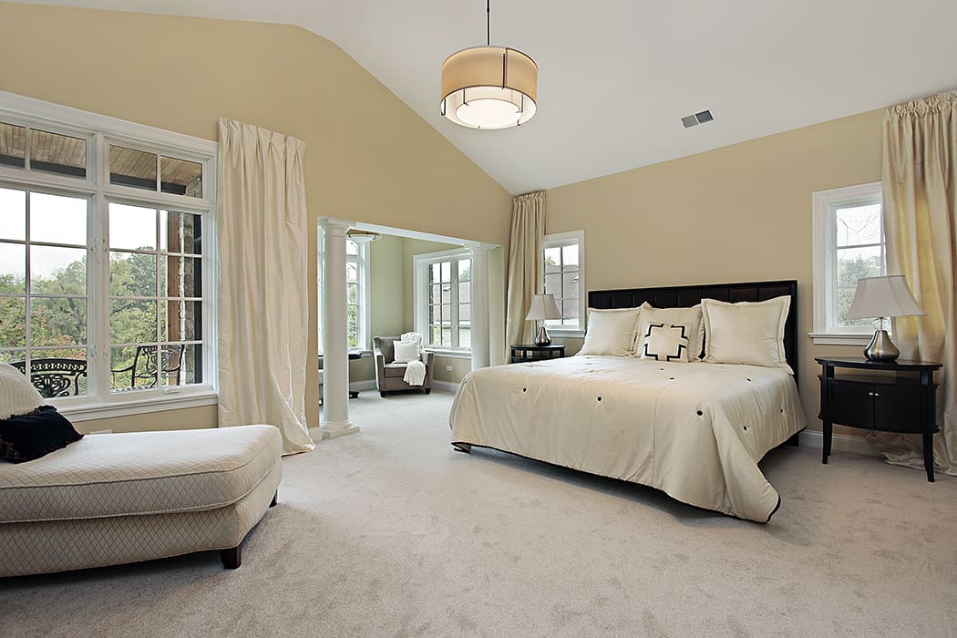 Beautiful white and cream colored bedroom with plush carpet